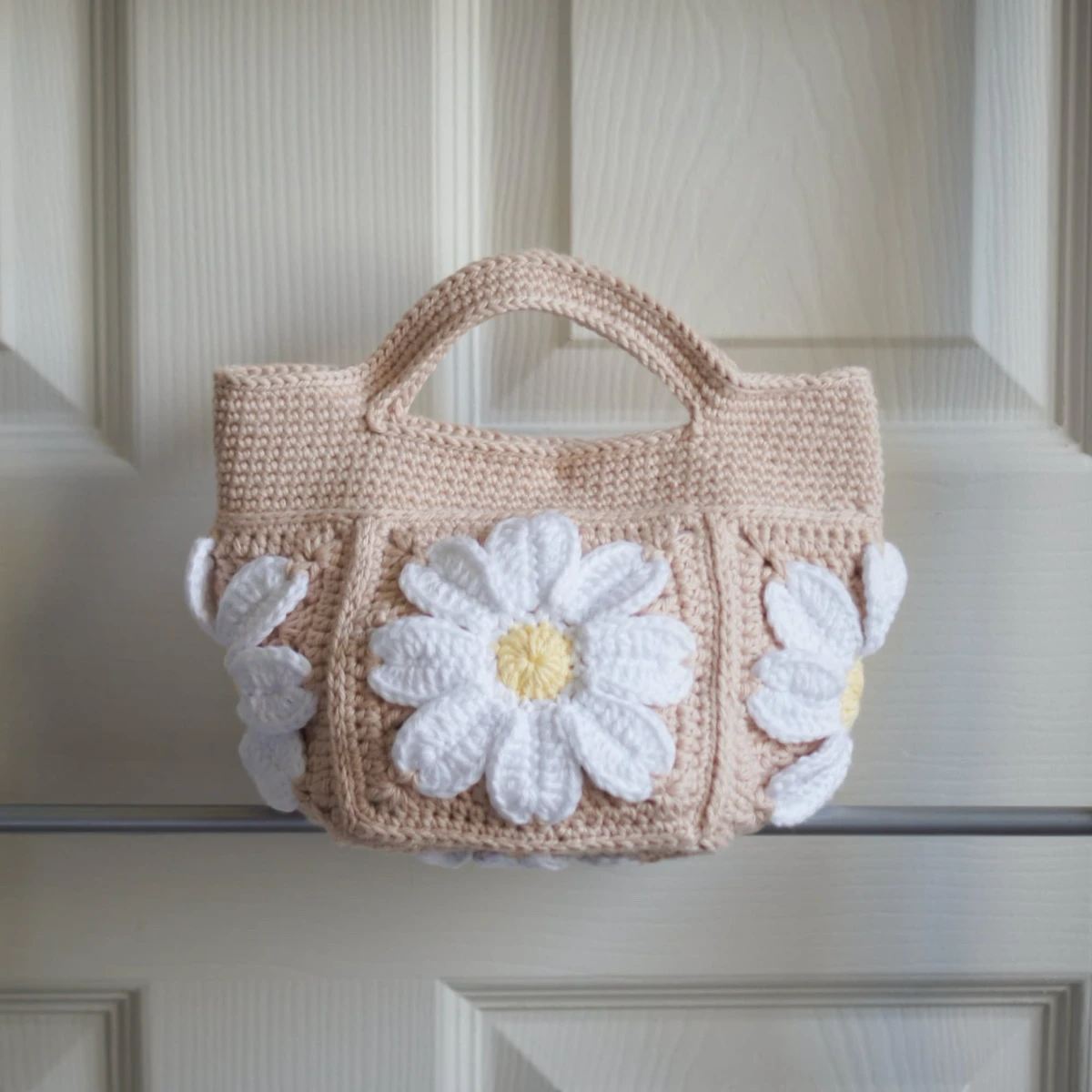 crochet daisy mini tote bag in beige on a rack