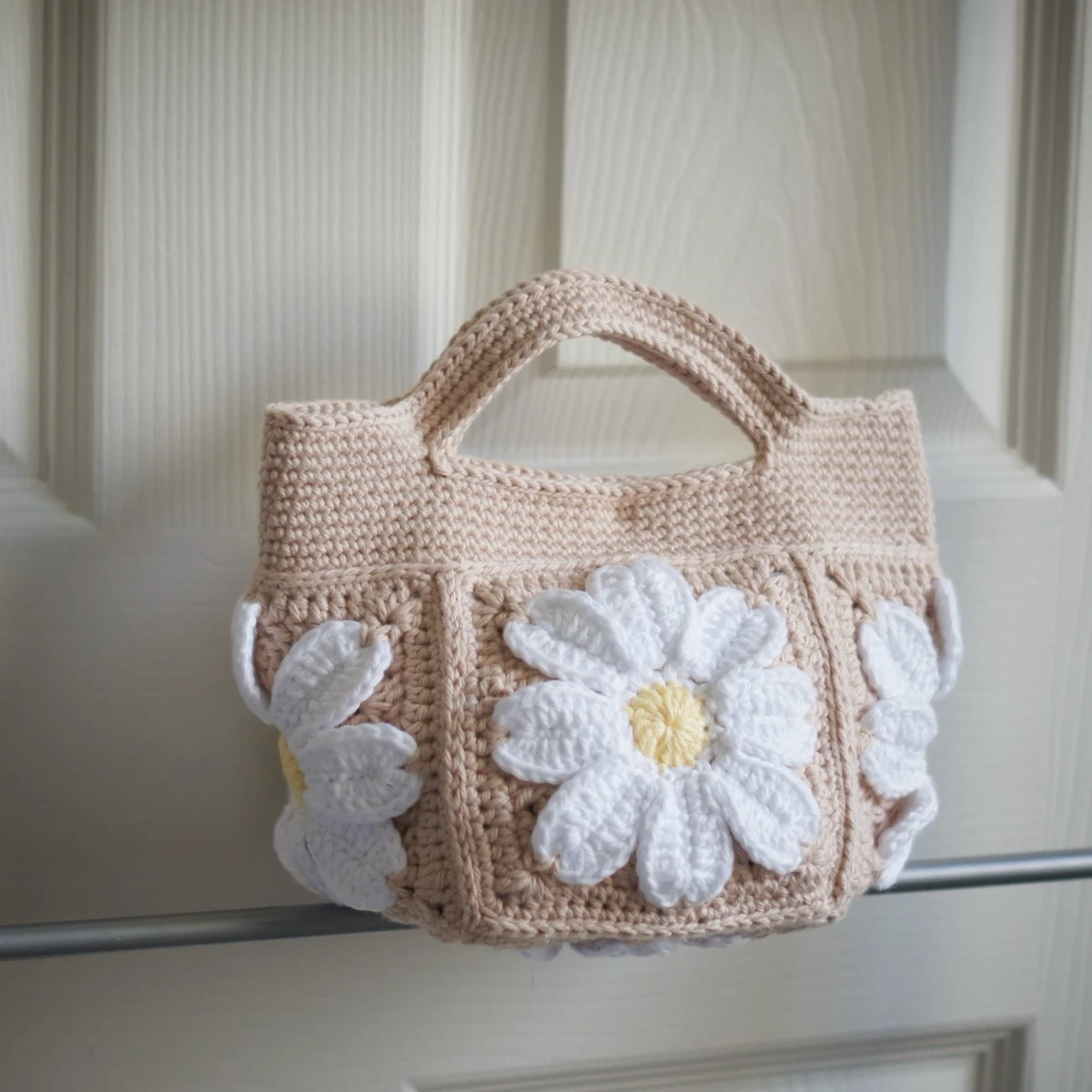 crochet daisy mini tote bag in beige on a rack