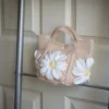 crochet daisy mini tote bag in beige on a rack