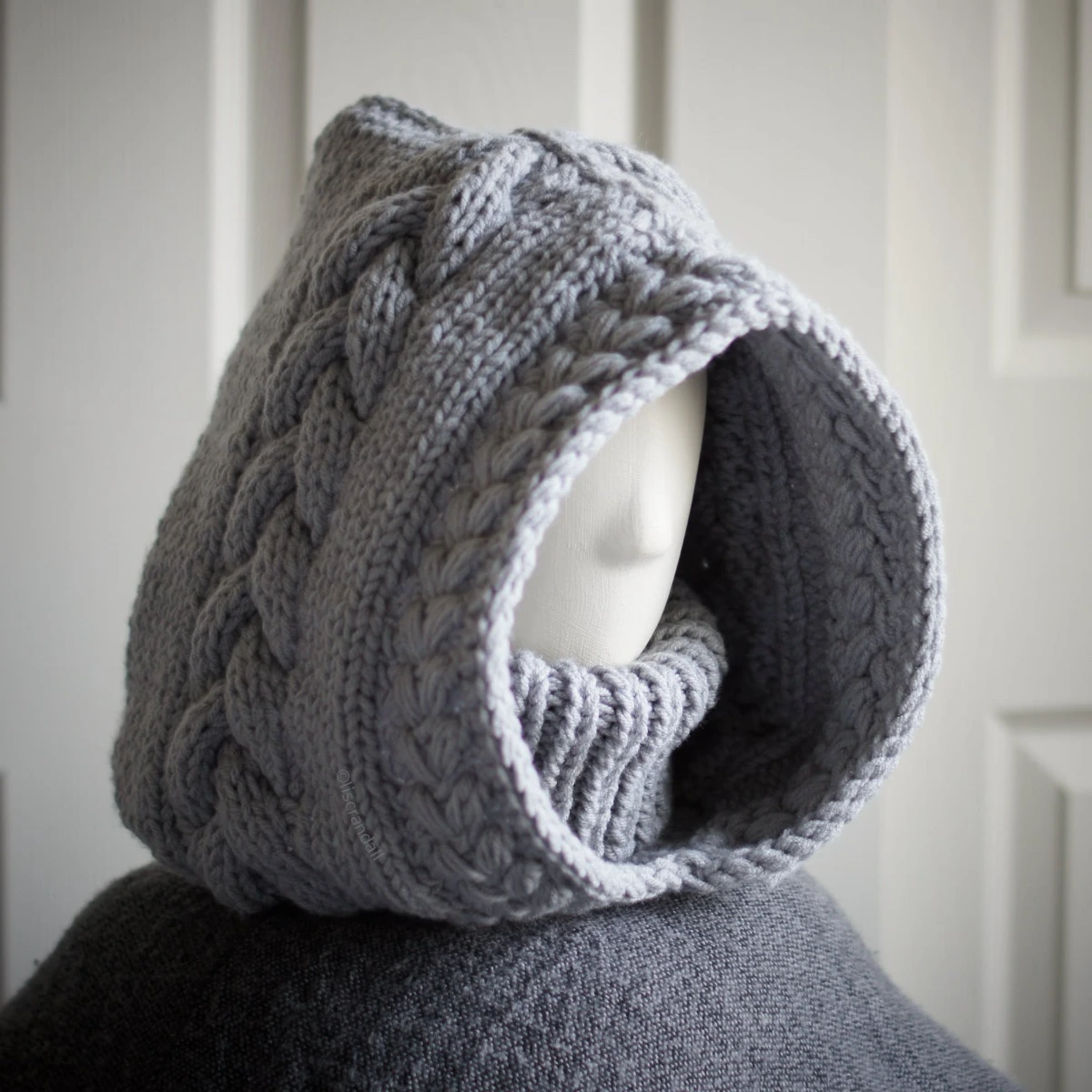 Handmade knitted balaclava in light grey with cable details and wheat stitch edging, side view showing cable details