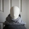 Handmade knitted balaclava in light grey with cable details and wheat stitch edging, front view with hood dropped back