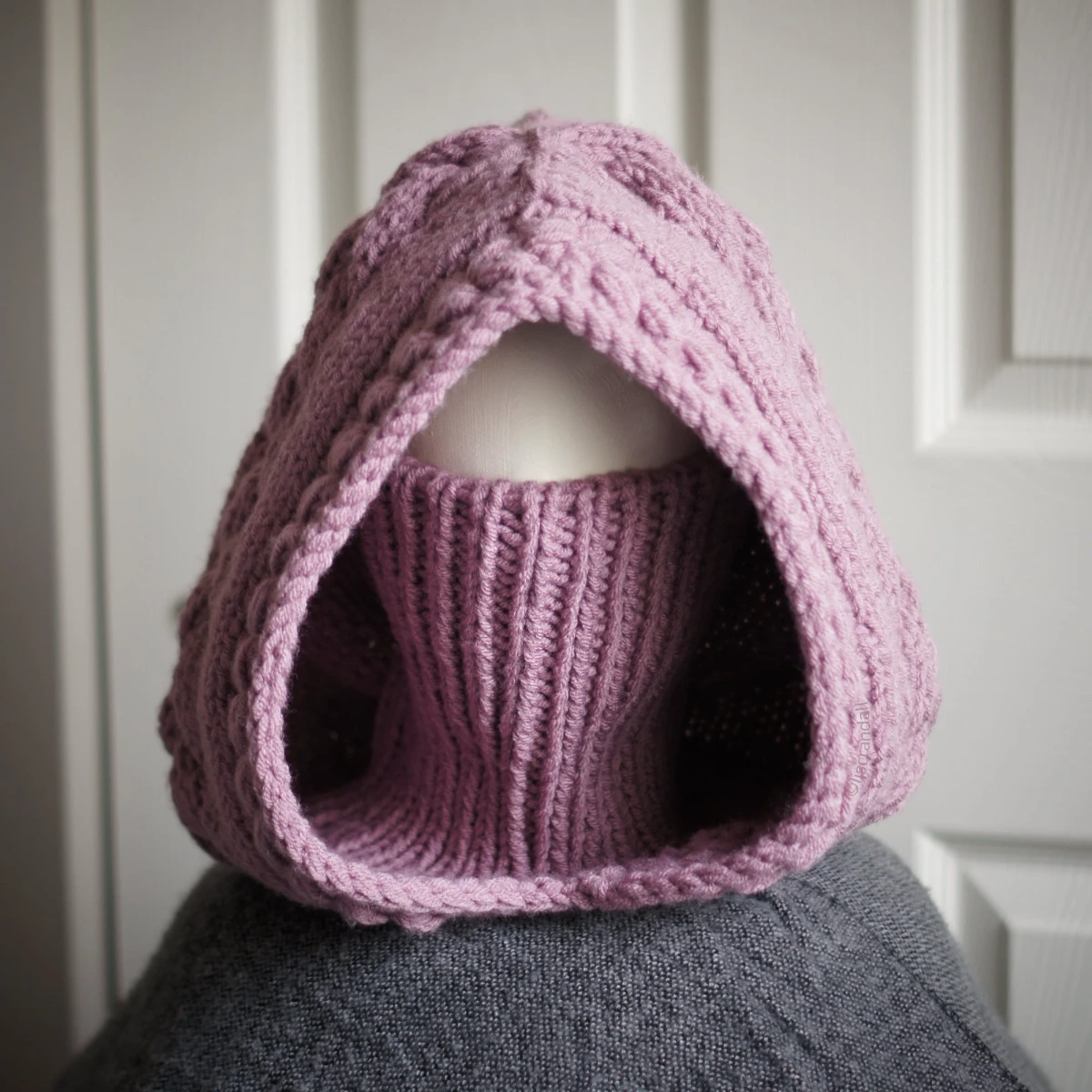 Chunky knit balaclava in mauve with cable details and wheat stitch edging, front view with face covering with turtleneck piece