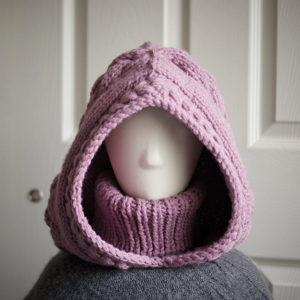 Chunky knit balaclava in mauve with cable details and wheat stitch edging, front view with turtleneck