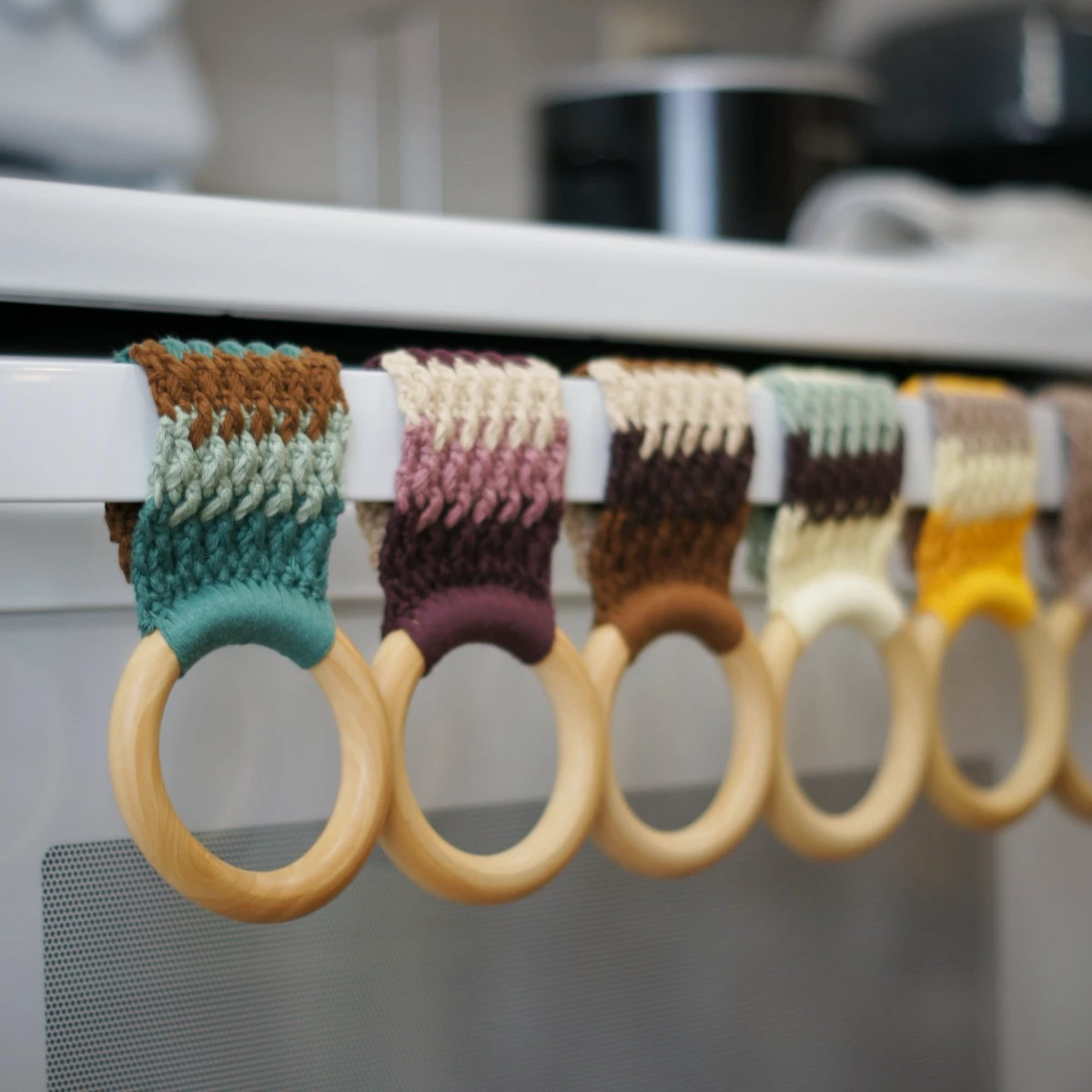 Crochet kitchen towel holders in various colors with wooden rings