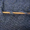 Denim blue merino wool with a strand of cashmere wool on bamboo knitting needle over knitted fabric