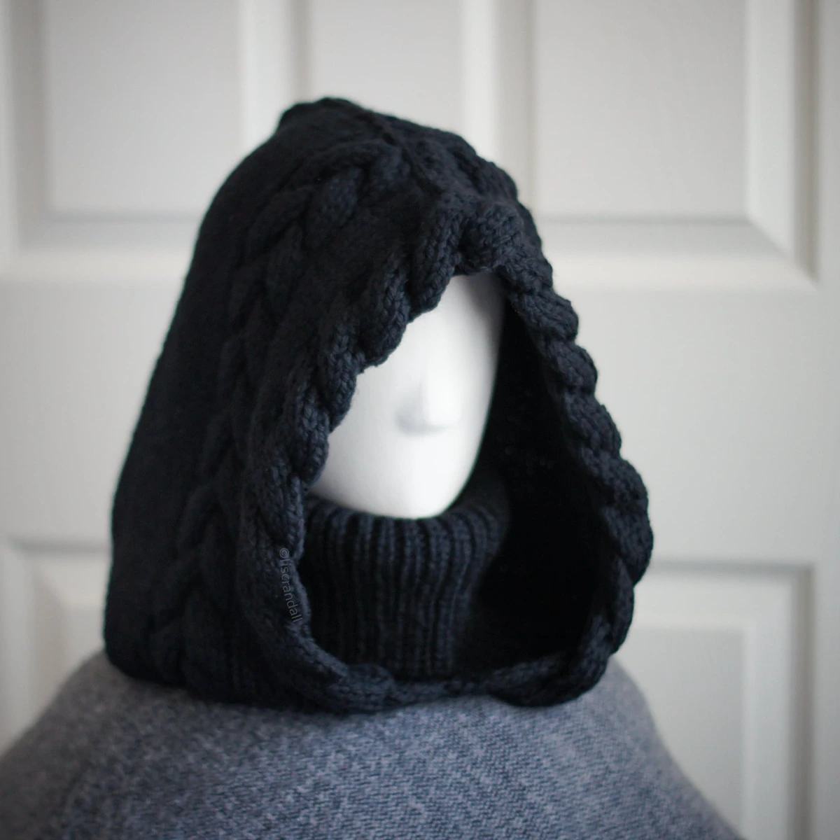Black merino knit balaclava hood with twist edging and folded turtleneck worn by mannequin, side view