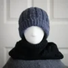 Black merino knit balaclava hood with twist edging and folded turtleneck worn by mannequin, hood dropped down