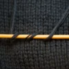 Merino cashmere sample with yarns coiling around bamboo knitting needle