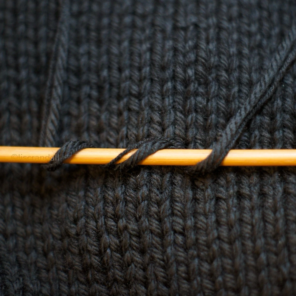 Merino cashmere sample with yarns coiling around bamboo knitting needle