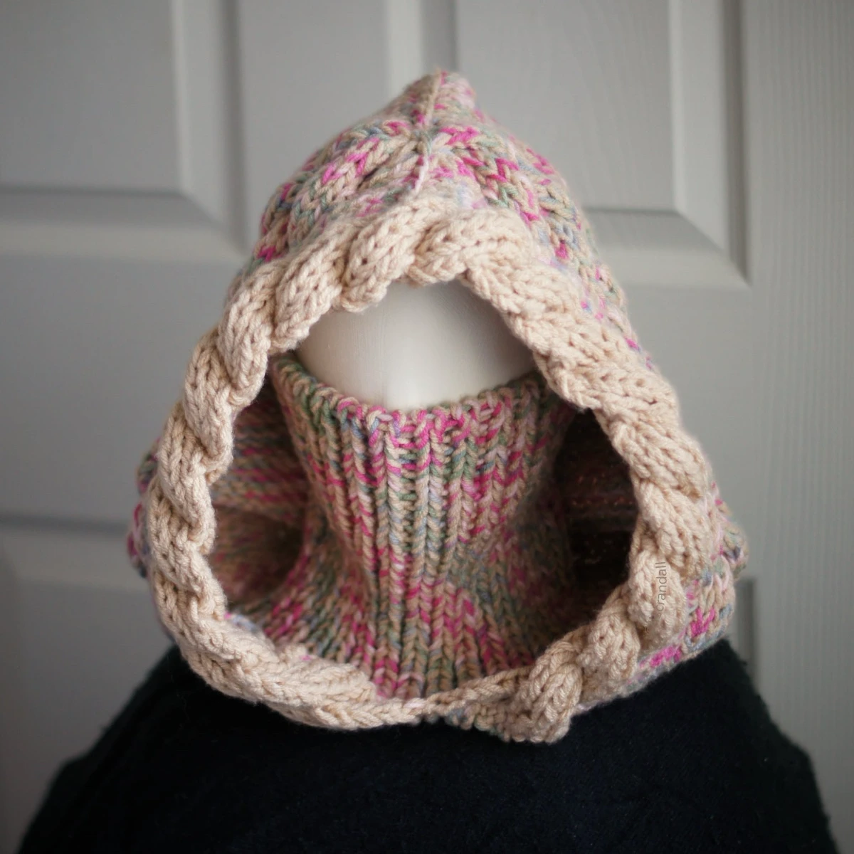 Oatmeal sprinkles knit balaclava hood with twist edging and turtleneck rolled up to cover face, worn by mannequin
