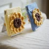 crochet sunflower squeeze pouch in yellow, side view, with blue pouch on the background