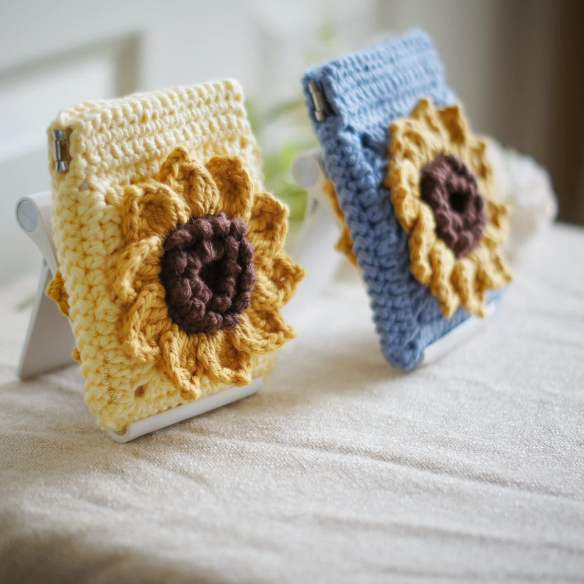 crochet sunflower squeeze pouch in yellow, side view, with blue pouch on the background