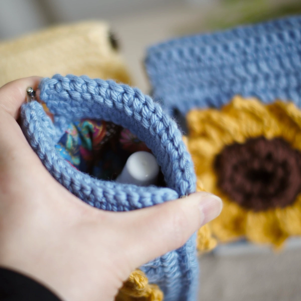 crochet sunflower squeeze pouch with a hand squeezing the clasp to demonstrate the opening